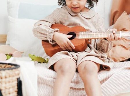 a-girl-in-ackecked-long-sleeve-dress-playing-brown-acoustic-3662767